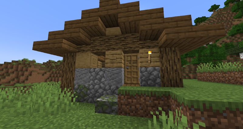 A simple wooden shelter with a sloped roof at dusk, built from stacked blocks